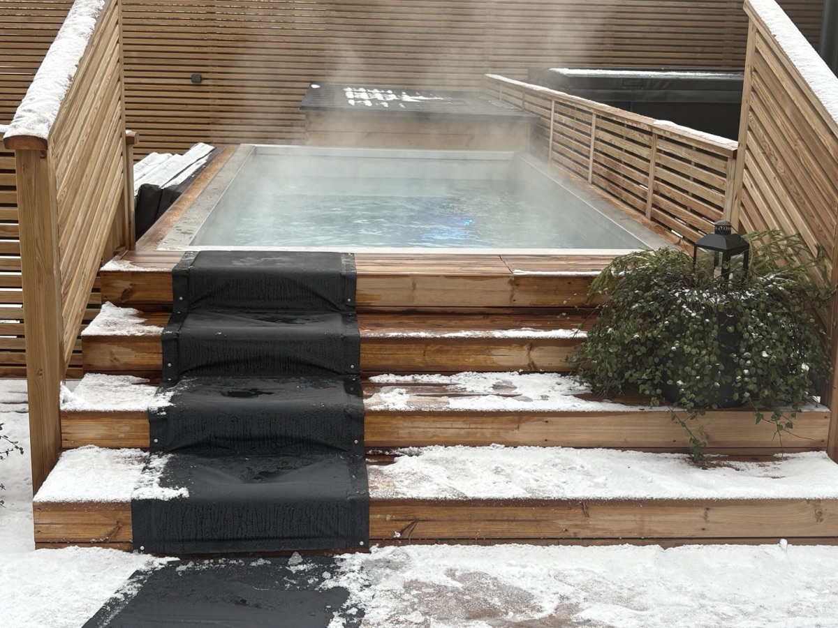 Steaming outdoor pool with snow-dusted timber steps at Teivaan Hehku, Lahti